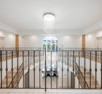 A staircase in a family house with a metal railing and a hanging light fixture.