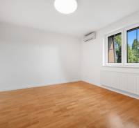 A bright room with wood-patterned flooring, air conditioning, and a radiator in a family house.