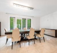 Dining room in a family house with a large table, cream chairs, view of the garden.