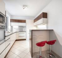 A kitchen in a family house with a modern bar counter and red chairs.