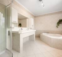 Bathroom with a bathtub and a shower in a family house with tiled flooring.