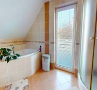 A bathroom in a family house with a bathtub, a shower, and access to a balcony.