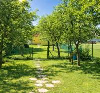 The garden of a family house in Poprad with a lawn, trees, and a stone path.