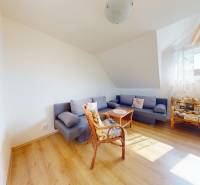 Living room in a family house with a sofa, an armchair, and a wooden-patterned floor.