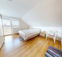 A bright bedroom in a family house with a wood-decor floor and simple furnishings.