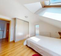 A bedroom in a family house with a wooden decor floor and light furnishings.