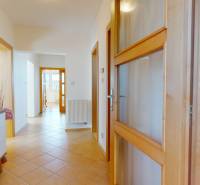 A hallway in a family house with tiles, white furniture, and wooden doors.