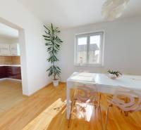 A kitchen with a dining area in a family house with a wooden decor floor and a large window.