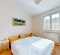 Bedroom in a family house with a bed, nightstands, and a wooden decor floor.