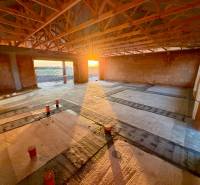 A family house under construction in Andovce, with a concrete floor and exposed walls.