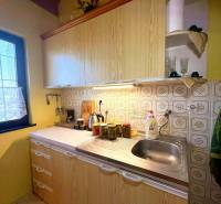 A kitchen in a cottage with wooden decor, light countertops, yellow walls.