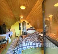 Attic room in a cottage with wooden walls and a bed, simple furnishings.