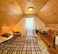 Attic room in a cottage with a bed, wooden beams, and a guitar.