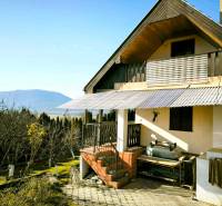 A cottage in Partizánske with a view of the mountains, surrounded by a garden and trees.