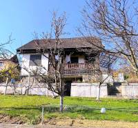 A cottage in Partizánske surrounded by trees with a staircase and a lawn.