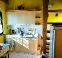 A kitchen in a cottage with wooden decoration, retro tiles, and yellow walls.