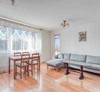 Living room in a three-room apartment with a wooden decor floor, dining table, and gray sofa.