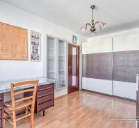 A room in a 3-room apartment with a desk, a floor with a wooden decor, and a wardrobe.