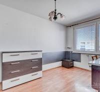 A room with prismatic lighting, white furniture, and a wood-patterned floor.