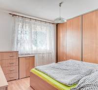 Bedroom in a 3-room apartment with wood-patterned flooring, wardrobe, bed, furniture.