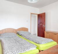 A bedroom in a 3-room apartment with two beds and a wooden decor floor.