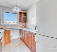 A kitchen in a 3-room apartment with a wooden decor floor, equipped with a sink and a stove.