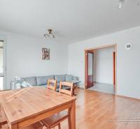 Interior of a 3-room apartment with a wooden decor floor, dining table, and sofa.