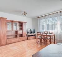 Living room in a three-room apartment with a wooden decor floor, furniture, and a dining table.