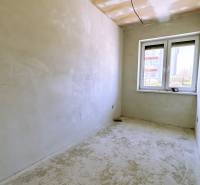A room in a family house with a window and plastered walls, without floor covering.