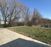 The garden of a family house in Klasov with paving and a fence in the background.