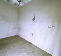 An unfinished room in a family house with exposed electrical installations and white wall paint.