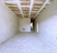 A spacious room in a family house without finished flooring and wall painting.