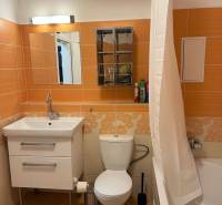 A bathroom with orange tiles, a bathtub, a sink, and a toilet in a 3-room apartment.