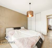 Bedroom in a family house with a bed, wardrobe, and wooden decor flooring.