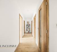 A narrow hallway with a wooden decor floor and a bookshelf in a family house.