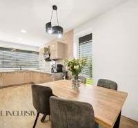 A kitchen in a family house, with a dining table, a wooden-patterned floor, and floral decorations.