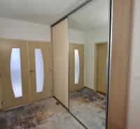 A hallway in a 2-room apartment with a large mirror and light-colored furniture.