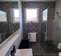 Modern bathroom in a 2-room apartment with a glass shower enclosure and decorative tiles.