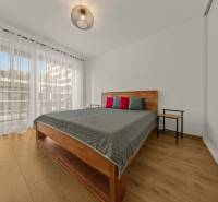 A bedroom with a bed, tables, and a wooden decor floor in a two-room apartment.
