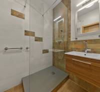 Bathroom with tiles and a wooden decor floor in a 2-room apartment.