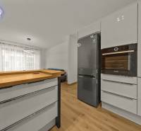 Modern kitchen in a 2-room apartment with wood-patterned flooring and stainless steel appliances.