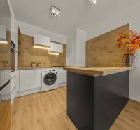 A kitchen with wooden decor, a washing machine, appliances, a floor with wooden decor, in a 2-room apartment.