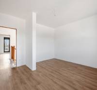 Interior of a family house with a wood-patterned floor and white walls.