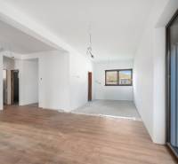 Interior of a family house with a window, white walls, and a floor with a wood decor.