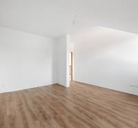 A spacious room with light walls and a floor with a wooden decor in a family house.