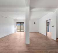 A spacious room in a family house with a wooden decor floor and glass doors.