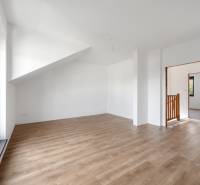 A bright room in a family house with a wooden decor floor and a sloped ceiling.