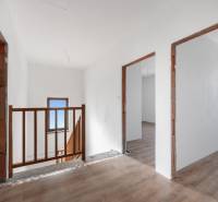 A hallway in a family house with a wooden decor floor and wooden railing.