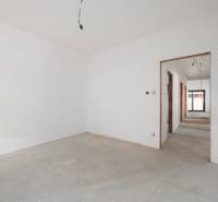 Empty room in a family house with white walls and a raw floor.