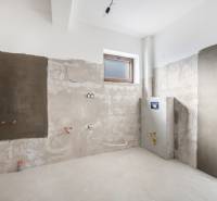 An unfinished room in a family house, ready for renovation, with a window and rough walls.